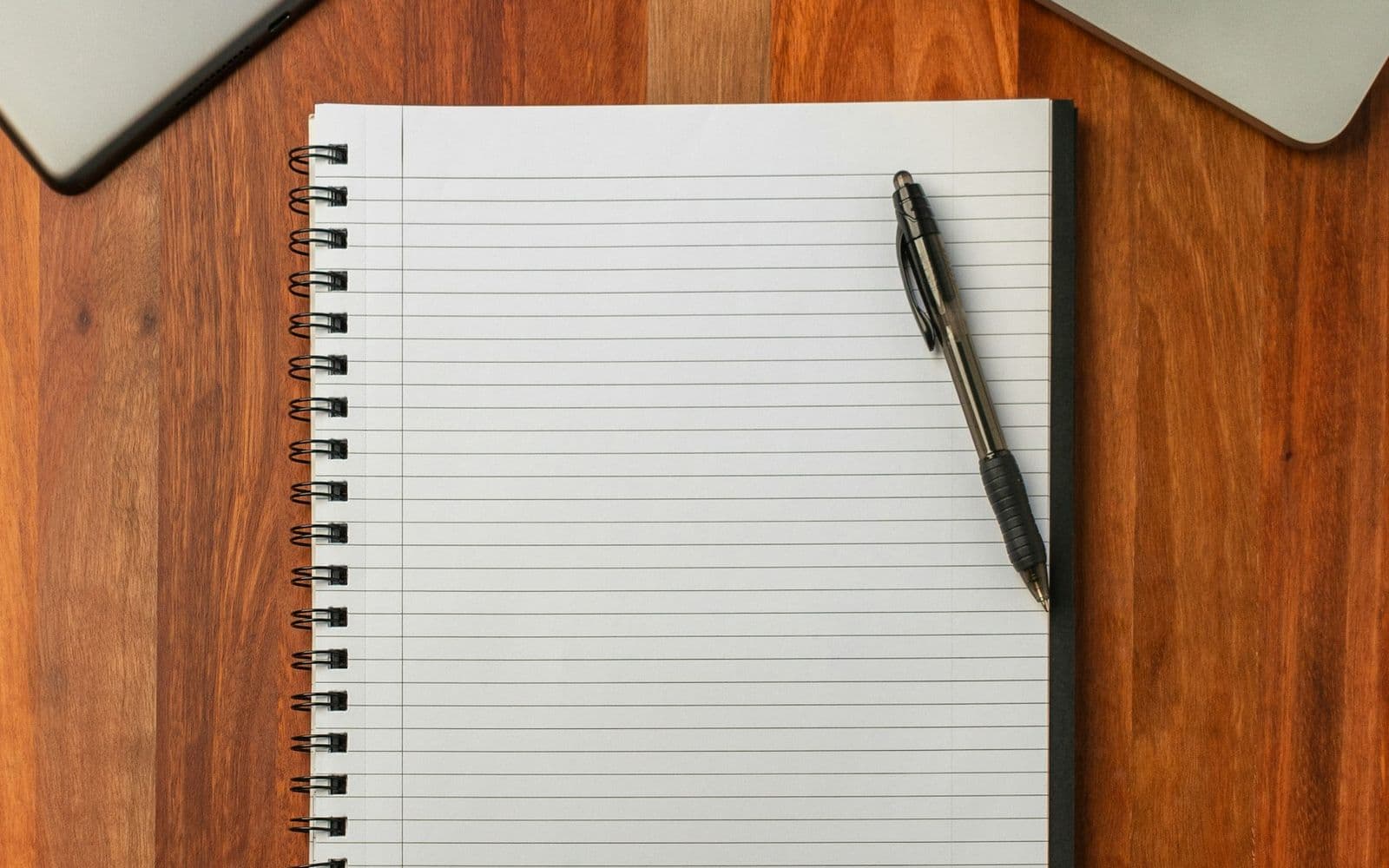 Cuaderno con una lapicera sobre un escritorio de madera