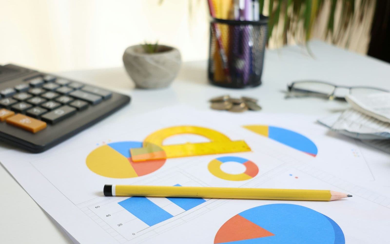 Desk with calculator, pie charts and a pencil